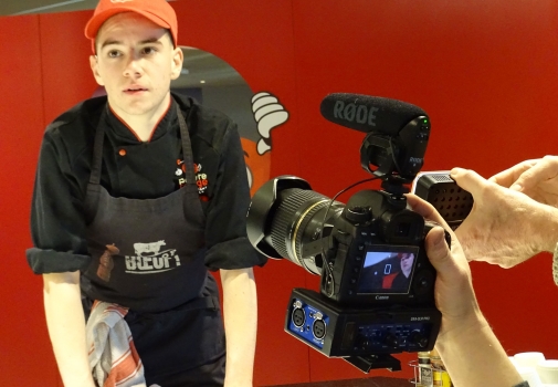 Photo d'une camera filmant un jeune homme au travail pendant le tournage d'un épisode
