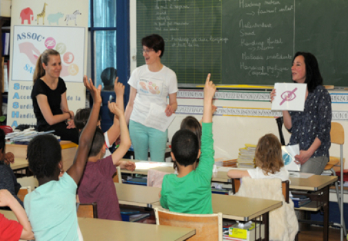Atelier handicap dans une salle de classe avec des enfants qui lèvent la main 